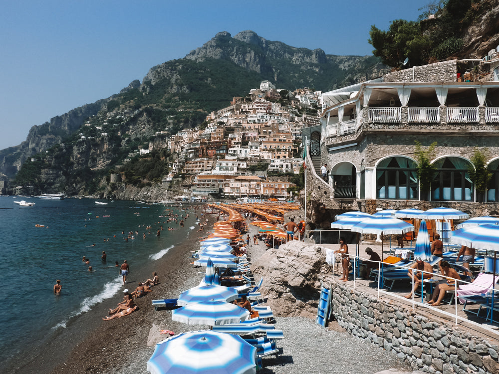 Positano beach on the Amalfi Coast Italy . European summer and long hot summer beach days under striped parasols and refreshing swims in the Mediterranean sea.